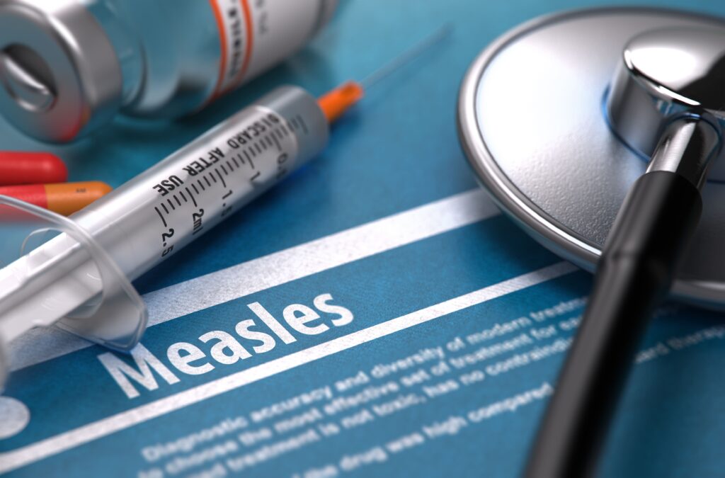 The word 'Measles' spelled out with a syringe and stethoscope placed nearby.