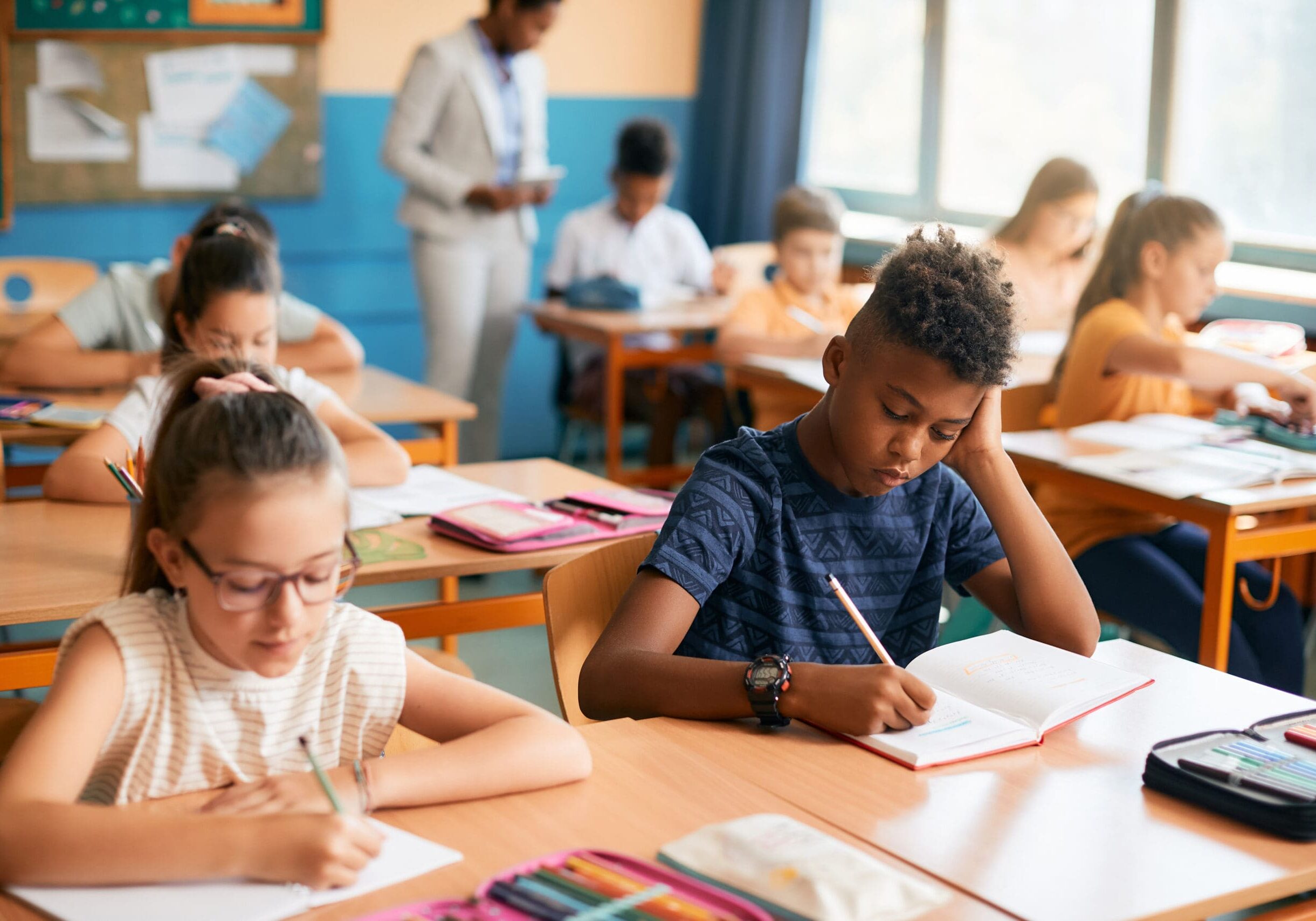 Elementary students writing dictation during class in the classroom.